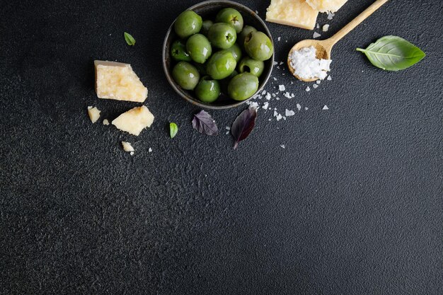 Photo olives vertes avec parmesan et sel sur fond sombre vue du dessus