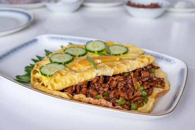 Omelette au boeuf frit avec des légumes sur une table blanche