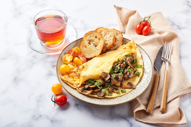 Omelette aux champignons et persil en assiette sur fond de marbre. Frittata - omelette italienne pour le petit déjeuner ou le déjeuner.