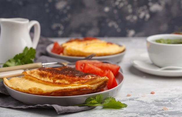 Omelette aux œufs brillante avec fromage et légumes, tasse de thé vert. Concept de nourriture de petit déjeuner, espace de copie.