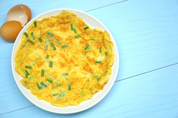 Omelette aux oignons verts sur une table en bois bleue