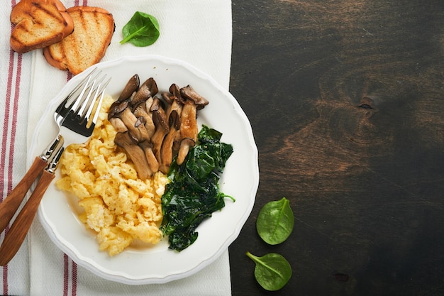 Omelette épinards pleurotes et omelette au fromage ou frittata sur fond de bois ancien foncé Idée de petit-déjeuner Vue de dessus avec espace de copie