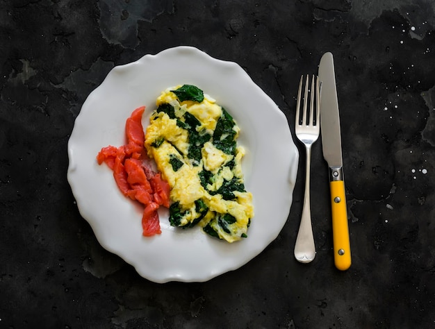 Omelette d'épinards et saumon légèrement salé délicieux petit déjeuner brunch sur un fond sombre vue de haut