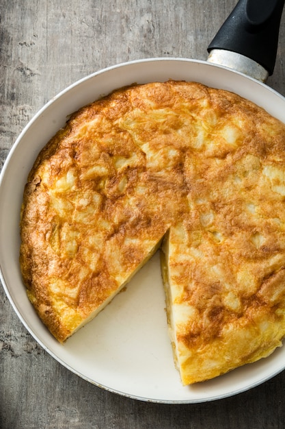 Omelette espagnole sur une poêle à frire sur une table en bois, vue de dessus