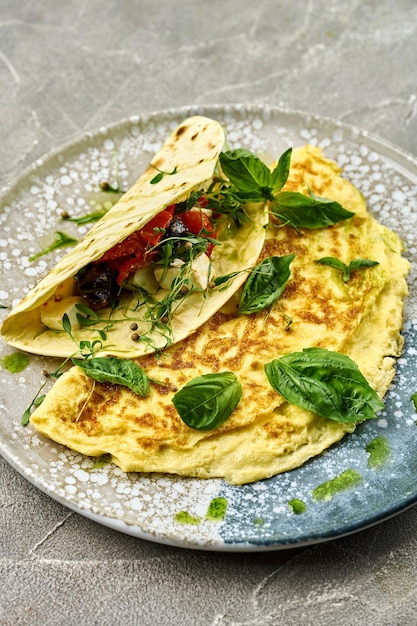 Photo omelette française aux poivrons rôtis, olives kalamata, tacos feta dans une assiette sur fond gris photo pour le menu