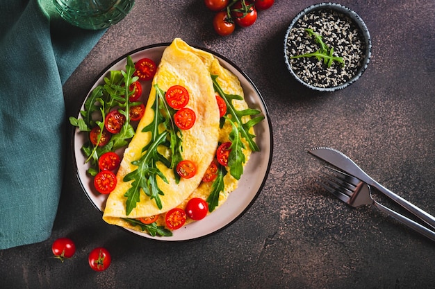 Omelette française remplie de tomates cerises et de rogues sur une assiette sur le dessus de la table