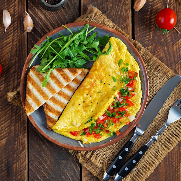 Omelette frite aux tomates, oignons et herbes. Délicieux petit déjeuner avec des œufs et des toasts. Vue de dessus