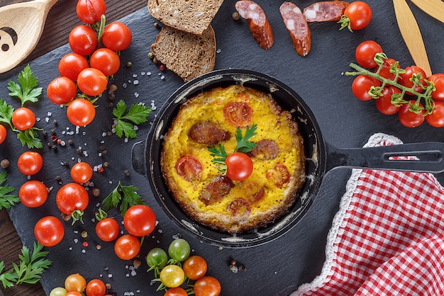 Omelette frite à partir d&#39;œufs de poulet avec tomates cerises rouges et saucisses fumées