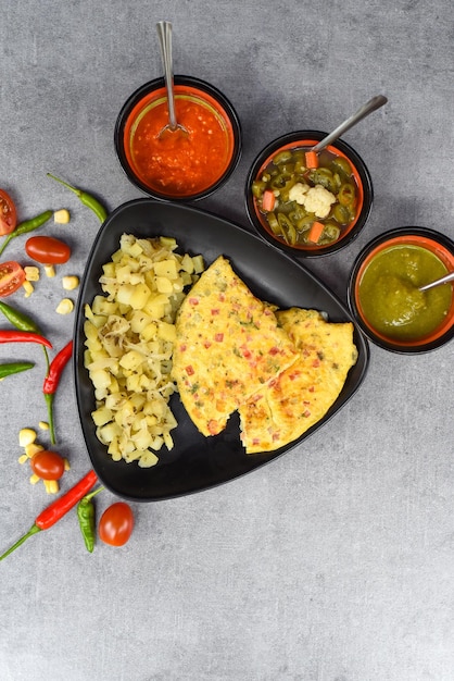 Omelette mexicaine aux pommes de terre sur plaque noire avec de la nourriture latino-américaine sur fond gris