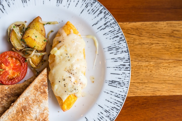 Omelette à la pomme de terre, tomates persil et fromage feta et pain en plaque blanche sur bois