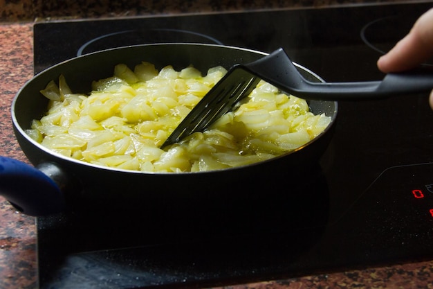 Omelette de pommes de terre espagnole traditionnelle cuisinant dans une poêle à frire sur une plaque vitrocéramique