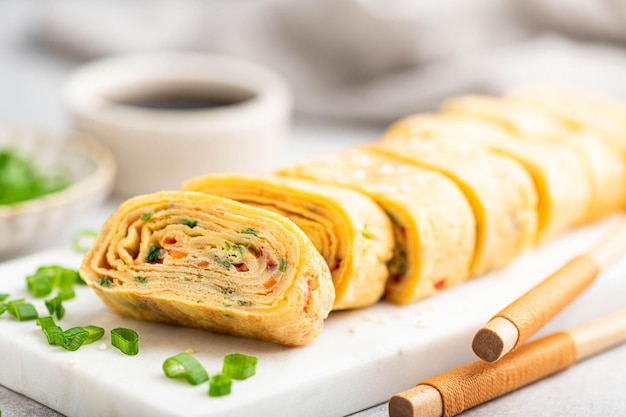 Photo omelette roulée japonaise tamagoyaki sur une plaque en céramique