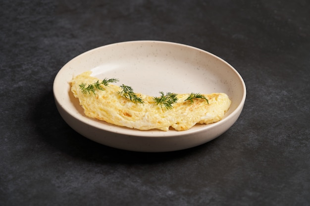 Omelettes de petit déjeuner traditionnel sur une plaque blanche sur fond sombre