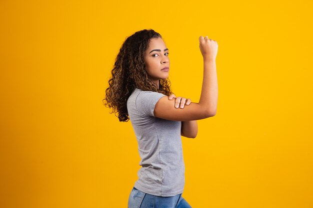 On peut le faire. Le poing féminin du pouvoir féminin. Femme victime de racisme. Abus au travail. Le pouvoir féminin. Autonomisation des femmes. La force des femmes. Fond jaune.