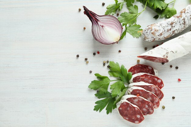 Ã Â¡oncept de nourriture savoureuse avec des saucisses de salami sur fond de bois blanc