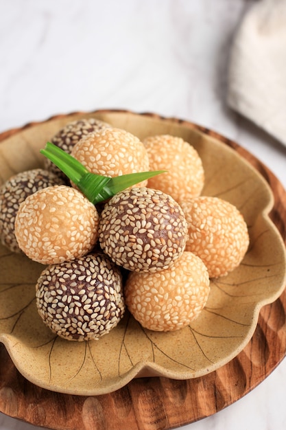 Onde-onde ou boule de graines de sésame de riz gluant, servi sur une assiette de Bali de style traditionnel indonésien. Fermer. Snack indonésien populaire avec influence chinoise