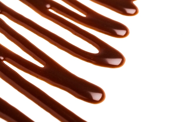 Ondulation de la sauce au caramel au chocolat sur un fond blanc uni