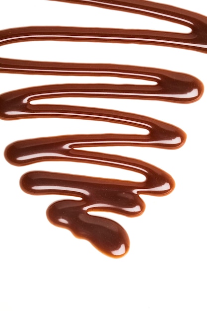 Ondulation de la sauce au caramel au chocolat sur un fond blanc uni