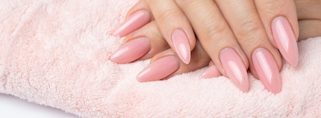 Des ongles élégants et à la mode, des mains de jeune femme, manucure rose sur fond blanc.