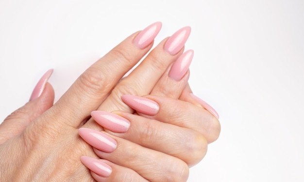 Des ongles élégants et à la mode, des mains de jeune femme, manucure rose sur fond blanc.