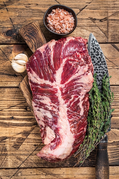 Onglet ou bifteck de viande de bœuf cru sur planche de boucher avec un couteau. table en bois. Vue de dessus.