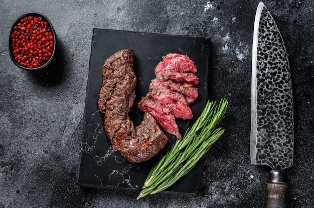 Onglet grillé en tranches de steak tendre suspendu sur une planche de marbre