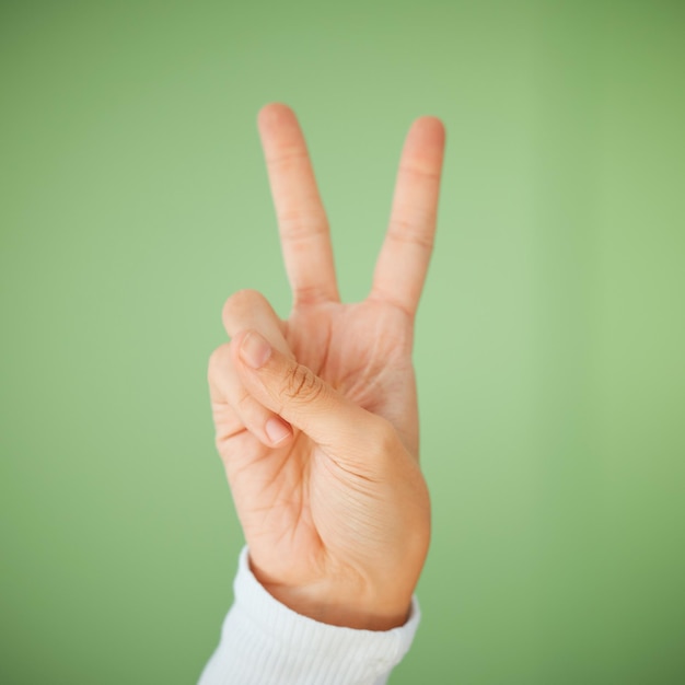 Ont été la tête se cogner à la positivité Photo d'une femme méconnaissable montrant le signe de la paix sur un fond vert