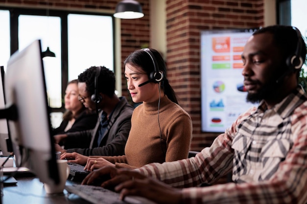 Opérateur Asiatique Travaillant Comme Assistant Commercial Au Service De Centre D'appels, Aidant Les Clients Au Support Client. Consultant En Télécommunications Utilisant La Ligne D'assistance Téléphonique De Télémarketing à La Réception.