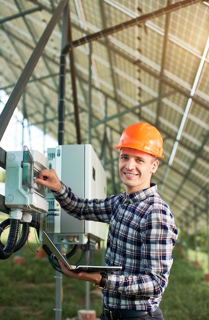 Opérateur en casque et avec ordinateur portable à la station vérifiant le fonctionnement de la centrale solaire