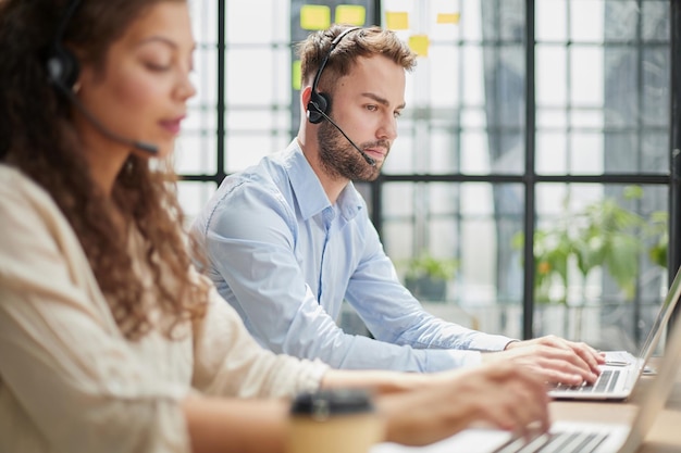 Photo opérateur de centre d'appels masculin avec un casque assis au bureau moderne