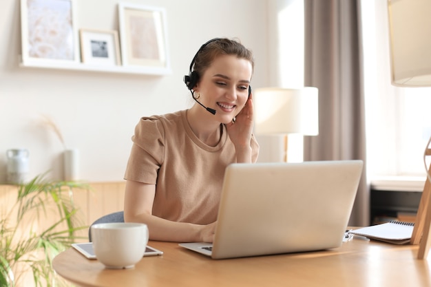 Opérateur indépendant parlant avec des casques et consultant les clients depuis le bureau à domicile.