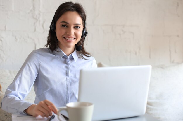 Opérateur indépendant parlant avec des casques et consultant les clients depuis le bureau à domicile.