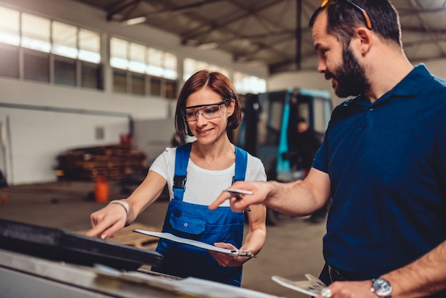 Opérateur de machine CNC femelle vérifiant le code du programme avec le superviseur