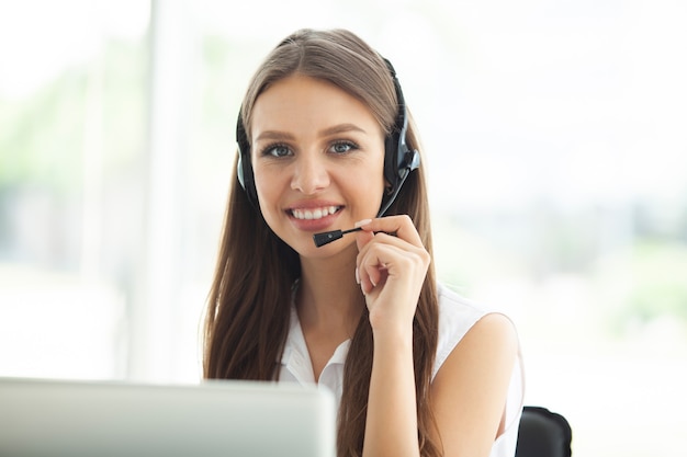 Opérateur de support client féminin avec casque et souriant.