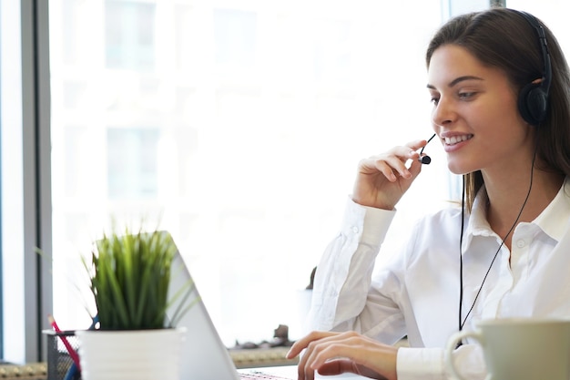 Opérateur de support client féminin avec casque et souriant.