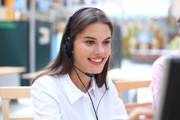 Opérateur de support client féminin avec casque et souriant.