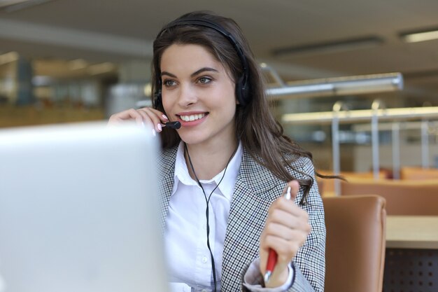 Opérateur de support client féminin avec casque et souriant.