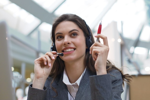 Opérateur de support client féminin avec casque et souriant.