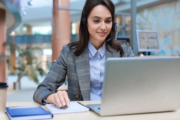 Opérateur de support client féminin avec casque et souriant.