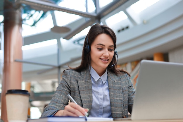 Opérateur de support client féminin avec casque et souriant.