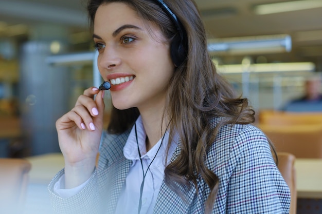 Opérateur de support client femme avec casque et souriant.