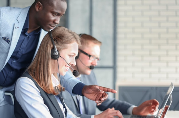 Opérateur téléphonique travaillant au bureau du centre d'appels aidant son collègue