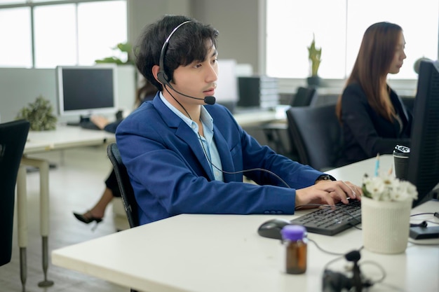 Les opérateurs asiatiques portent des écouteurs travaillant sur le lieu de travail.