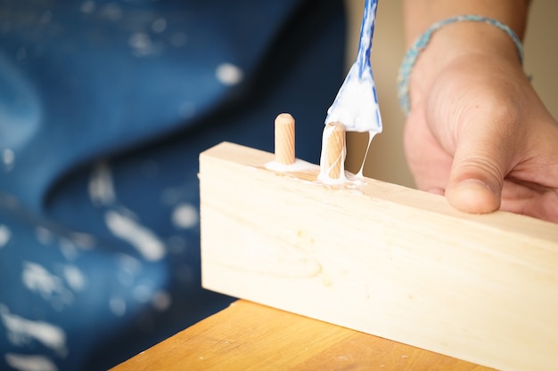 Les opérateurs de menuiserie utilisent de la colle pour assembler les pièces en bois à assembler et construire une table en bois pour leurs clients