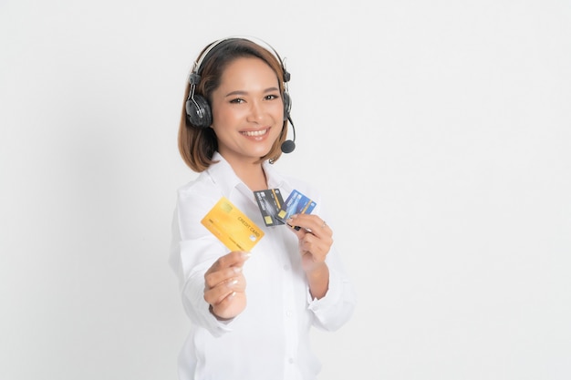 Une opératrice amicale ou un centre d'appels montrant une carte de crédit vierge, un casque tenant les bras croisés isolé sur une surface blanche