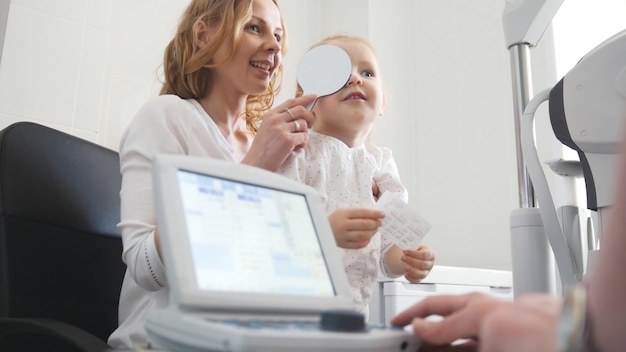 Ophtalmologie pour enfants - vue telephoti - optométriste vérifie l'oeil de la petite fille, gros plan