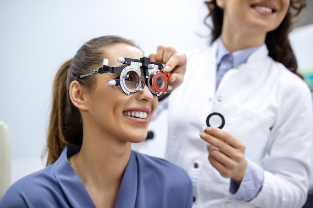 Ophtalmologiste examinant une femme avec un cadre d'essai optométriste patiente pour vérifier la vision dans une clinique ophtalmologique