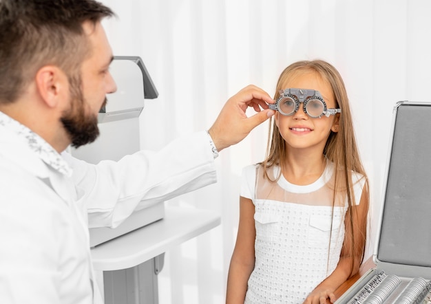 Ophtalmologiste examinant les yeux de la jeune fille avec un équipement spécial