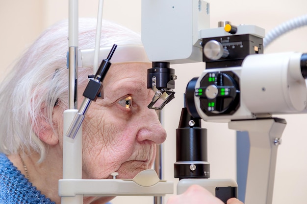 Un ophtalmologiste masculin vérifie la vue d'une femme adulte à l'aide d'un appareil moderne avec