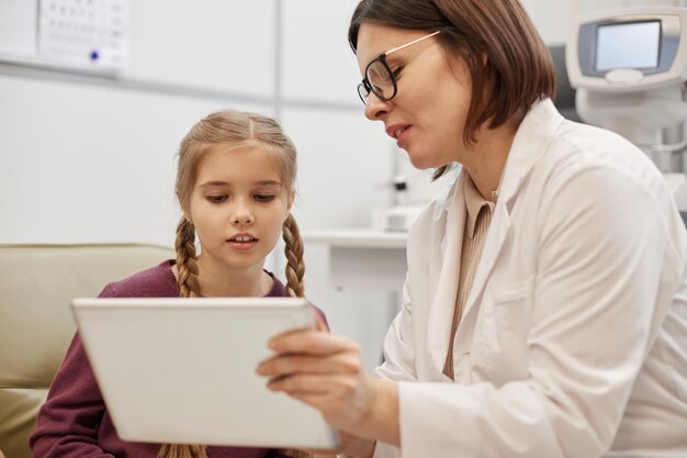 Photo l'ophtalmologiste parle à une petite fille